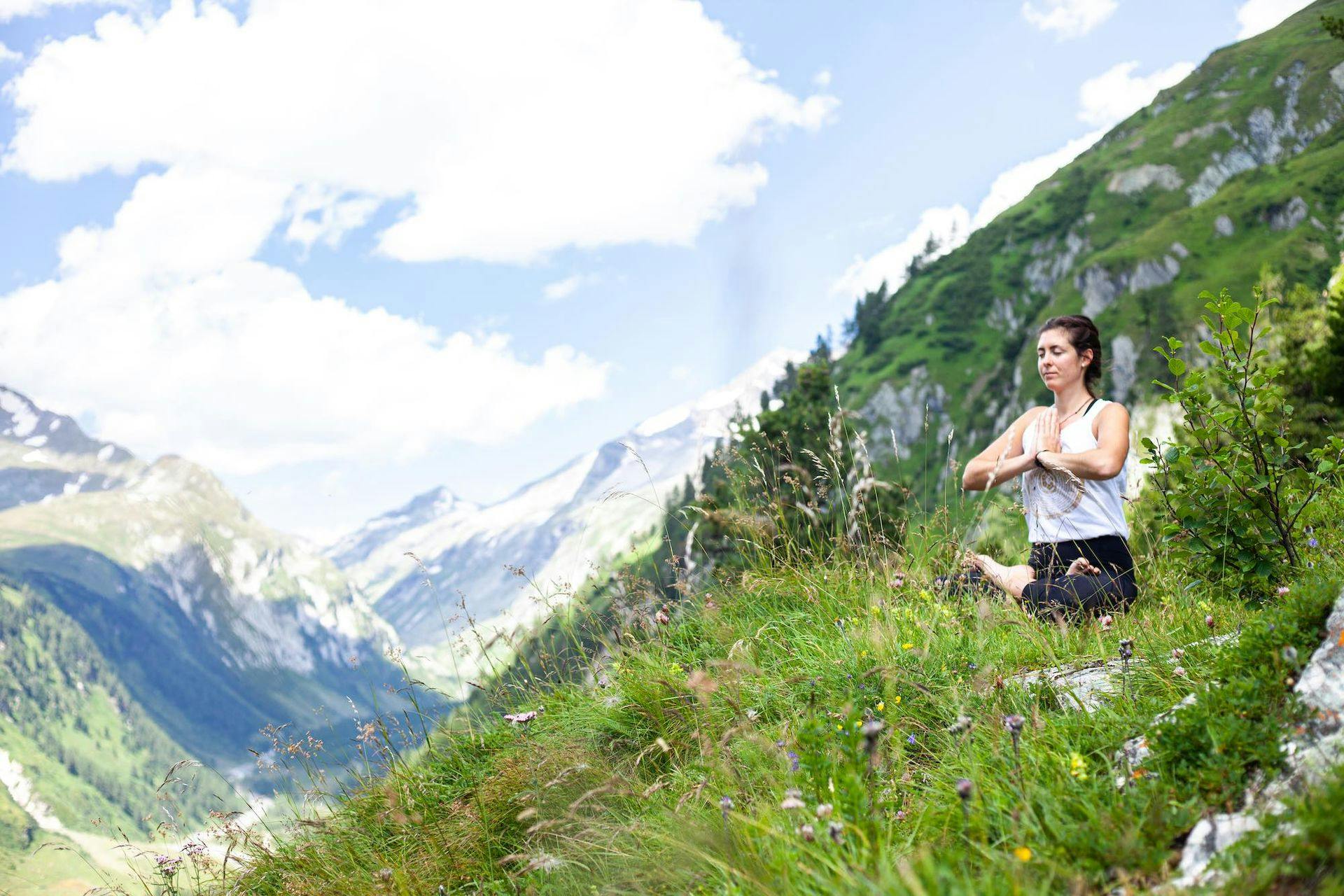 WOMAN sitting in lotus position in mountains