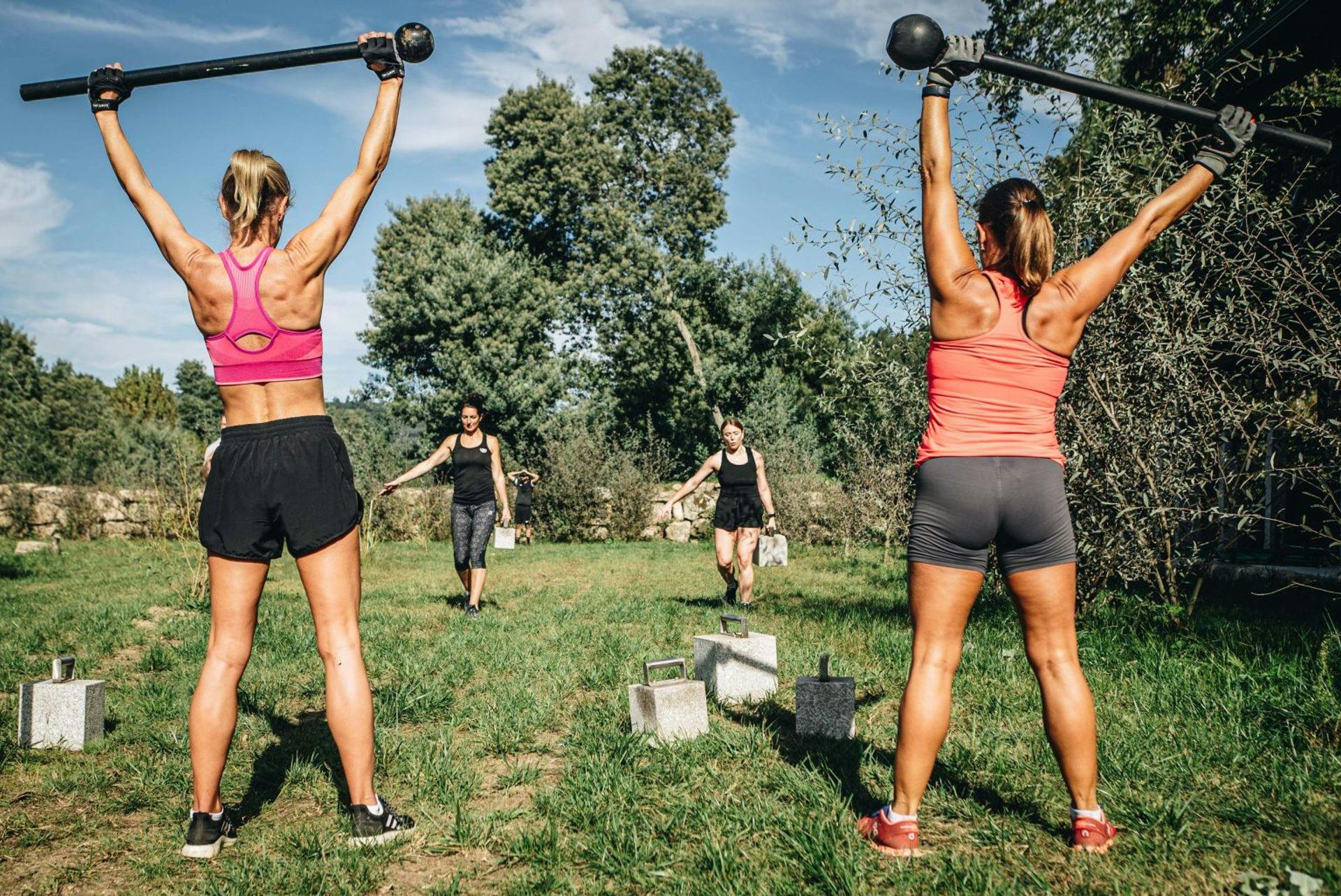 women lifting weights outside on grass
